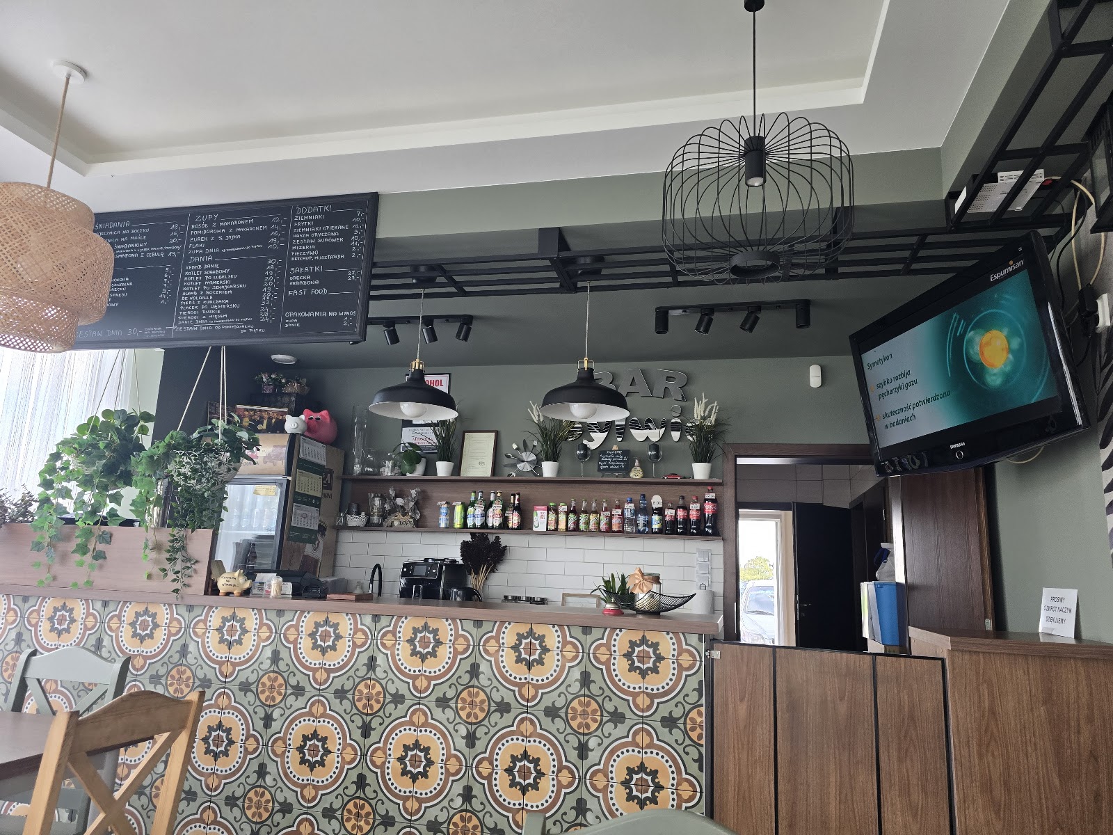 Przytulne wnętrze Baru Sylwia, lada z wzorzystymi kaflami i tablica domowego menu